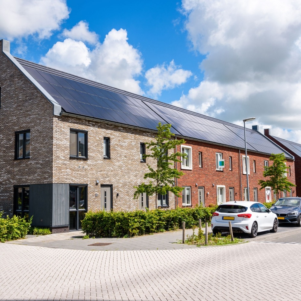 Rij nieuwe energiezuinige bakstenen rijtjeshuizen met het dak bedekt met zonnepanelen op een zonnige dag